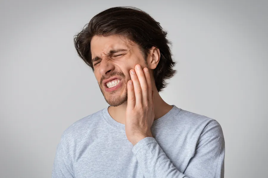Patient holding his cheek with dental discomfort